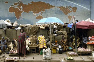 Women selling food at the market in front of a mural depicting a map of the world.