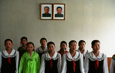 Schoolgirls in a secondary school sing for a foreign visitor.  Portraits of former Korean President Kim Il Sung (L) and his son Kim Jung Il (R) hang on the walls in all classrooms.