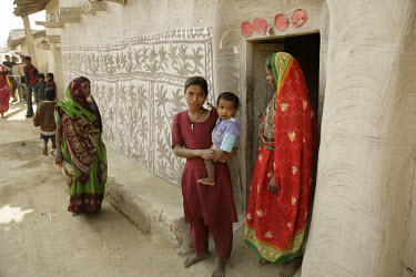 Women outside their traditionally painted houses in the village of Kharati, which is one of many settlements threatened with destruction by future coal mining and damming projects. Lacking title deeds...