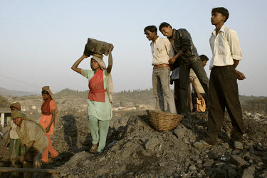 Adivasi tribal women carry coal at the Uramari coal dump while being watched by their managers who are non-tribal men. Most of the workers have migrated to the mining area having been displaced from t...