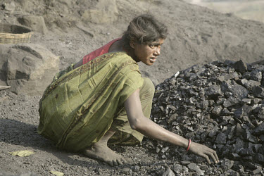 Woman working in a small coal dump, where workers collect coal for resale. Most of the workers have migrated to the area having been displaced from their traditional livelihoods in the countryside. La...