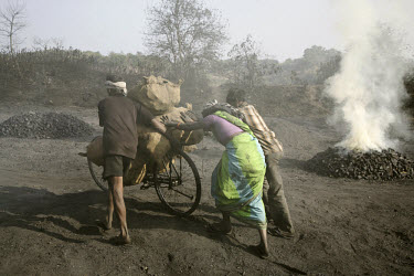 A family use a bicycle to carry coal they have collected for resale in a small coal dump. Most of the workers have migrated to the area having been displaced from their traditional livelihoods in the...