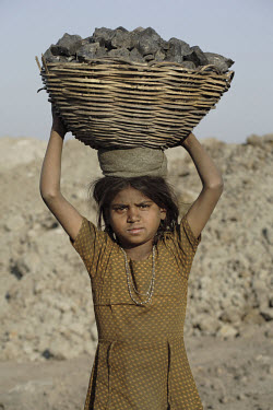 A young girl carries a basket of coal she has scavenged at the edge of the Jharia coal fields.