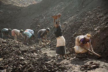 Workers move piles of ore from one heap to another before it is loaded onto trucks in a small iron ore mine. Most of the workers have migrated to the mining area having been displaced from their tradi...