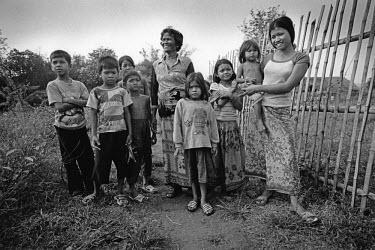 A group of women and children gather to watch a controlled explosion to destroy unexploded ordnance (UXO) which was discovered on land surrounding the village.