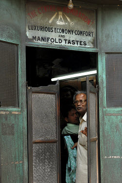 A barber stands in the doorway to his shop.