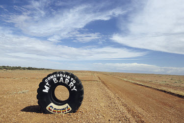 A painted tyre stands on the roadside at the exit from a farm in the outback.