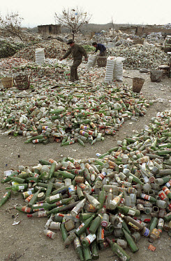 A man walks past over a pile of glass bottles for recycling in a municipal rubbish tip.