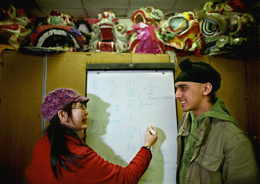 Kam (right) is being taught to speak basic Mandarin before he is introduced to his fiance Wing's parents, who are Hong Kong Chinese. Wing's friend Florence (left) is teaching him. Kam is a British Asi...