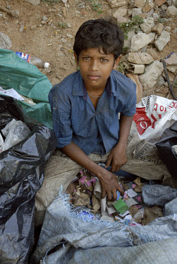 A young boy searches through rubbish bags for items to reuse or resell.