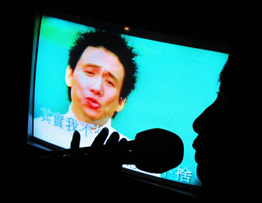 A woman sings into a microphone at a karaoke bar where young sex workers solicit clients. Many of the karaoke bars in China run brothels. Although prostitution is illegal and both the women and their...