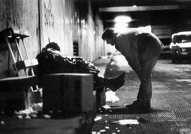 A volunteer working for the St Mungo's homeless charity helps a destitute man sleeping in an underground car park.