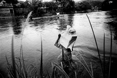 Traders carry large muslin sacks on their shoulders as they wade waist-deep through the waters of the Mae Sai River. The river, which marks the boundary of the Thai-Burmese border between Mae Sai and...