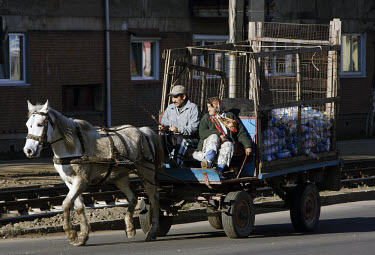 A Roma gypsy couple guide their horse-drawn recycling cart through the city.
