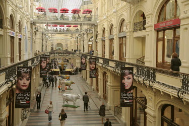 L'Oreal lipstick advertisements hang above shoppers browsing the arcade of boutiques and shops at The GUM State Department Store on Red Square.