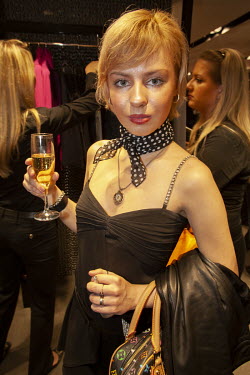 A wealthy young woman sips a glass of champagne at the opening of a new Dolce and Gabbana fashion boutique. The Russian nouveau-riche (nicknamed the ^New Russians^) have become renowned for flaunting...
