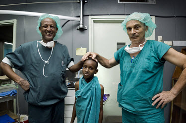AMREF medical specialists, Ethiopian doctor Asrat Mengiste and Swedish plastic surgeon Bill Adams-Ray, pose in their surgical gowns with a young patient just before an operation at KCMC hospital. AMRE...