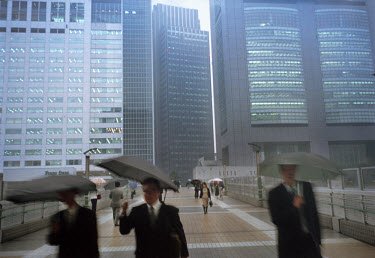 Businessmen with umbrellas returning home in the rain after work.