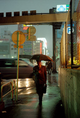 A business commuter with an umbrella walking through the rain.