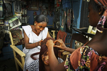 A woman has her hair braided in the Ajegunle slum.