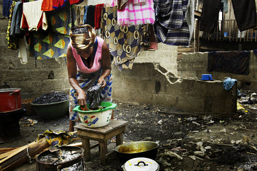 A woman prepares food for sale outside her house.