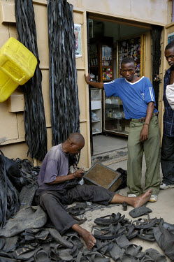 Recycling - David Magomwa making sandals from old truck tyres. He has been making these shoes in the same place, in a busy lane close to Kariakoo market, for 25 years.