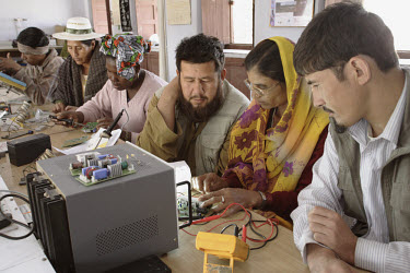 Barefoot College solar technology training for international students selected from villages in Afghanistan (two men in foreground), Ghana (woman centre) and Bolivia (woman with hat and man in backgro...