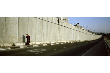 A Palestinian woman walking alongside the Israeli separation wall / barrier.