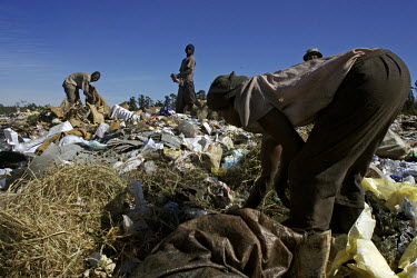 Unemployed and desperate, people scavenge through waste at a rubbish dump looking for items to sell.