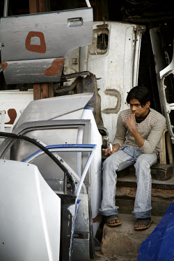 A man sits near a stack of car doors outside a shop in Old Delhi.