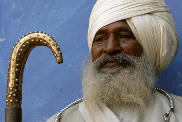 A wandering Sikh holy man sports the 'Whale Tail' beard, prayer beads on a ring around his neck. He also carries his decorated staff of office.