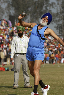 An elderly Sikh athlete wearing a Khanda pendant competes in the shot putt event at the annual Kila Raipur Sports Festival (also known as the Rural Olympics).