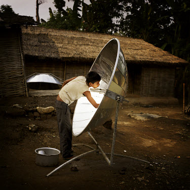 A youth cleaning a solar cooker at a Bhutanese refugee settlement. The cooker has to be cleaned after every meal in order to keep the surface working as effectively as possible. With the financial hel...