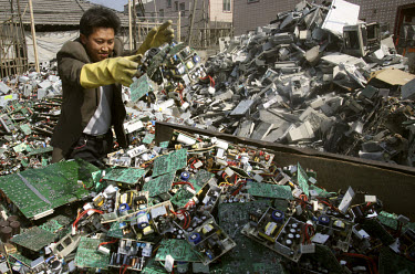 A migrant worker throws stacks of motherboards onto a cart to transport to a nearby e-waste recycling station. Every year Guangdong receives more than a million tons of computer waste from countries a...