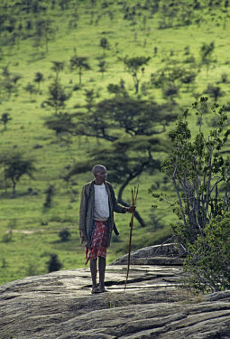 A Maasai guide stands on a rock on the edge of the Serengeti.
