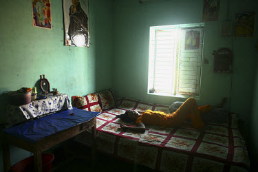 A young sex worker resting on a bed in a local brothel.