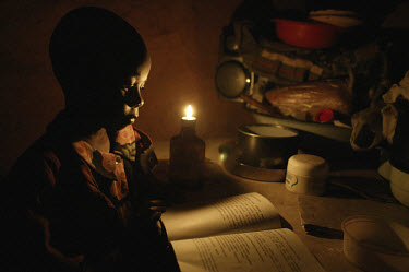 Talent, one of a family of five living in this tiny room, does his homework by the light of the one diesel oil lamp at home in the Nyamhuka suburb of Nyanga (known locally as the Dark City of Nyanga)....