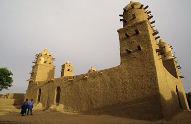 Two men walking past the main mosque, which was built from mud in the traditional Malian way.