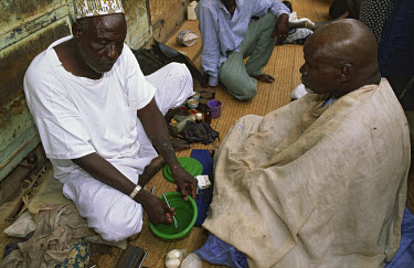 A roadside barber disinfecting his razor after attending an educational health awareness programme.