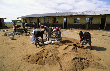 Women mixing cement to use in the building of a new school.