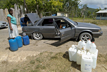 Jerry cans full of water are loaded into a car. Since there is no water supply in the hills, residents have to hire taxis to bring water from a source 10 miles away.