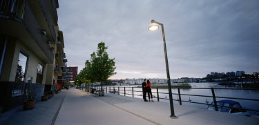 A couple standing near a street lamp outside the waterfront apartments in Hammarby Sjostad. The Hammarby Sjostad district, a former brownfield site, is now being redeveloped to provide environmentally...