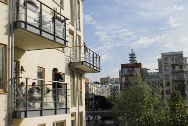 Residents relaxing on the balcony of a new luxury apartment building in Hammarby Sjostad. The Hammarby Sjostad district, a former brownfield site, is now being redeveloped to provide environmentally f...