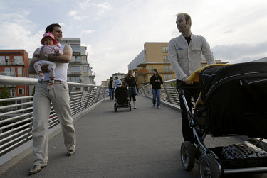A man pushing a pram while another carries a baby while out for a walk in Hammarby Sjostad. The Hammarby Sjostad district, a former brownfield site, is now being redeveloped to provide environmentally...