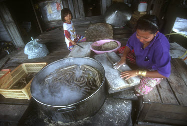 A woman cooking long fish sausages.