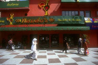 Muslim girls passing a Nando's chicken restaurant.