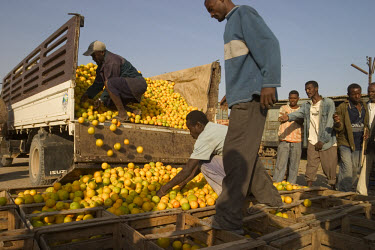 Traders loading locally produced oranges on to trucks at a wholesale market.