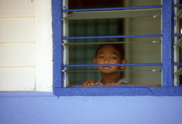 A young boy looking through the window of a care centre for children with mental health problems.