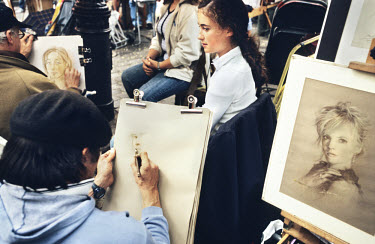 Street artists paint tourists' portraits near the basilica of Montmartre.