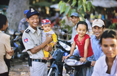 Policeman poses with a baby in his arms.